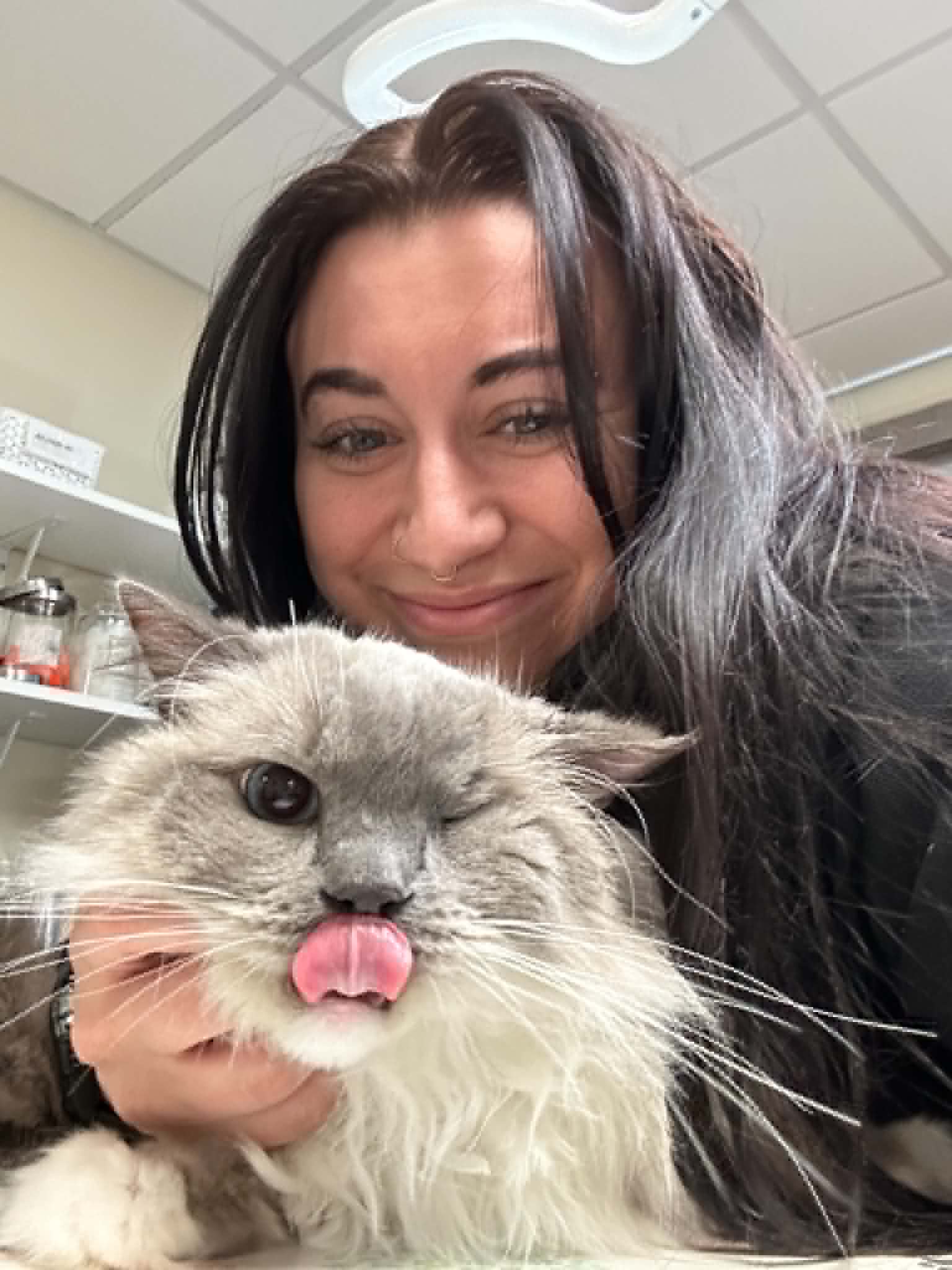 Bella smiling with a fluffy cat at the clinic